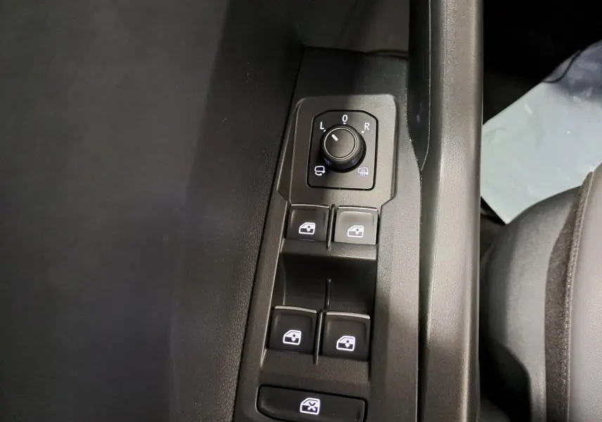 Gros plan sur les commandes de réglage des rétroviseurs et des vitres électriques côté conducteur du Volkswagen T-Cross 2022.