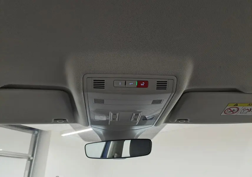 Vue intérieure du plafond avant du Volkswagen T-Cross bleu récif, montrant les commandes d'éclairage et le rétroviseur central.