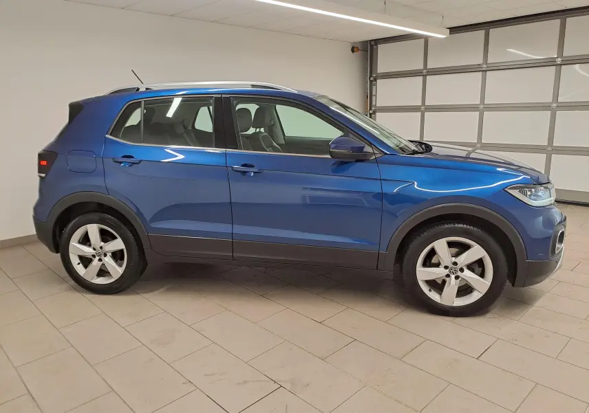 Vue de profil côté gauche du Volkswagen T-Cross 2022 bleu récif avec jantes alliage et protections noires basses.