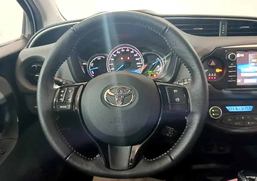Volant cuir noir de Toyota Yaris 2019 vu de face, avec tableau de bord et écran tactile affichant la climatisation.