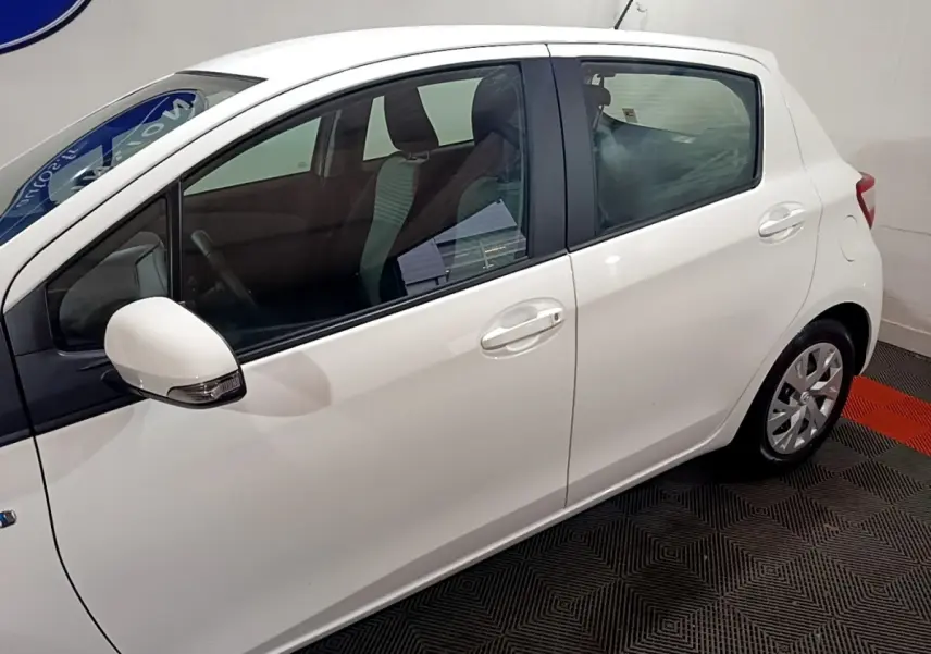 Vue latérale côté gauche d'une Toyota Yaris blanche 5 portes, avec rétroviseur blanc et jantes compactes.
