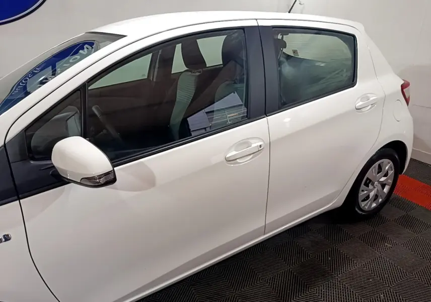 Profil côté gauche d'une Toyota Yaris blanche hybride 2019, avec rétroviseur blanc et jantes alliage visibles.