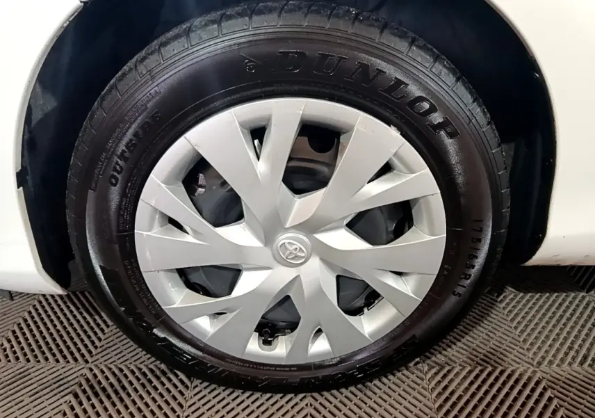 Gros plan sur la roue avant gauche blanche d'une Toyota Yaris 1.5 VVT-I Hybrid avec enjoliveur argenté et pneu Dunlop.