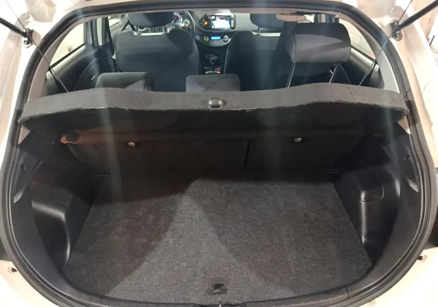 Coffre ouvert d'une Toyota Yaris blanche 2019, vue arrière montrant l'habitacle et la tablette de séparation.