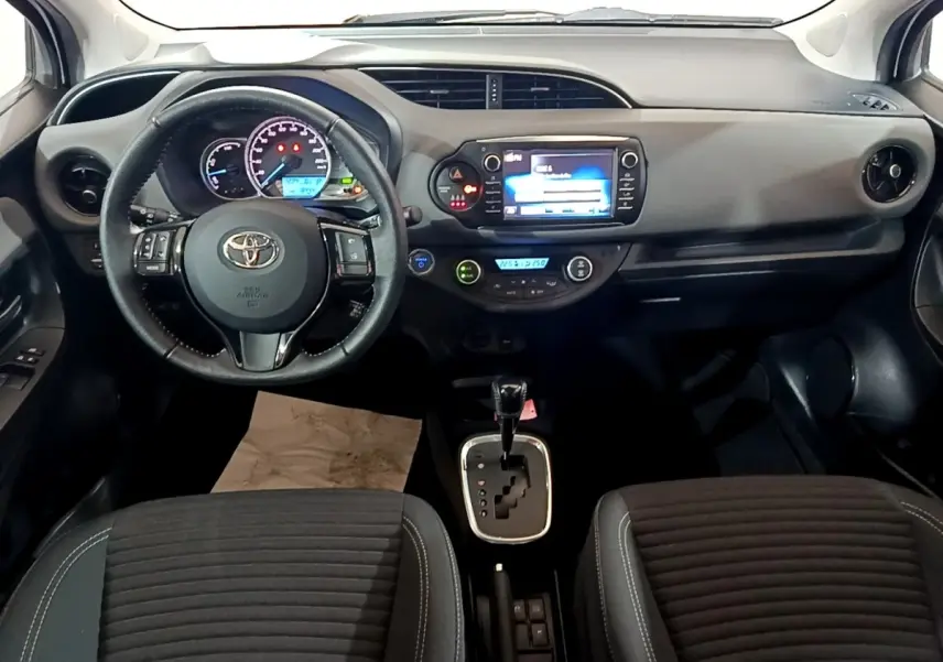 Vue intérieure frontale du tableau de bord et volant cuir de la Toyota Yaris hybride 2019 avec écran tactile central.