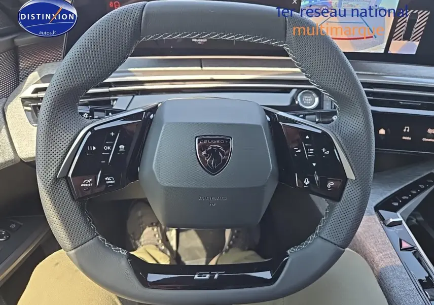 Vue intérieure centrée sur le volant cuir perforé noir du Peugeot 3008 1.2 hybrid GT avec logo et commandes multifonctions.