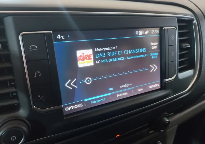 Gros plan sur l'écran tactile central du Peugeot Traveller 2021 affichant une station radio numérique.