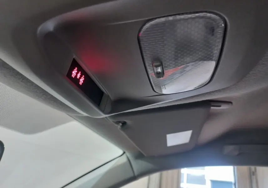 Vue intérieure du plafond avant du Peugeot Traveller gris clair 2021, montrant la console de plafonnier avec éclairage rouge et pare-soleil.