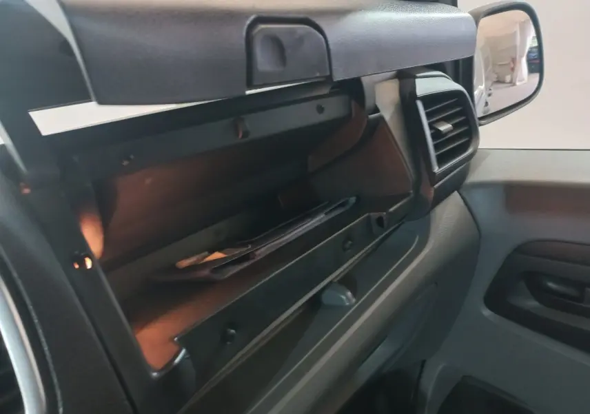 Gros plan sur la boîte à gants ouverte côté passager du Peugeot Traveller 2021, intérieur gris foncé.