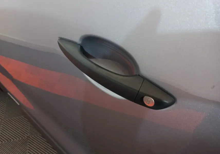 Poignée de porte noire sur la porte gris clair d’un Peugeot Traveller, vue en gros plan latéral.