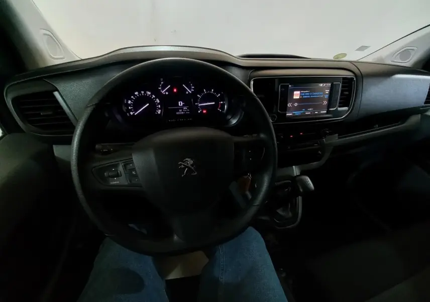 Vue intérieure centrée sur le volant et le tableau de bord du Peugeot Traveller 1.5 BlueHDi 120, avec écran tactile allumé.