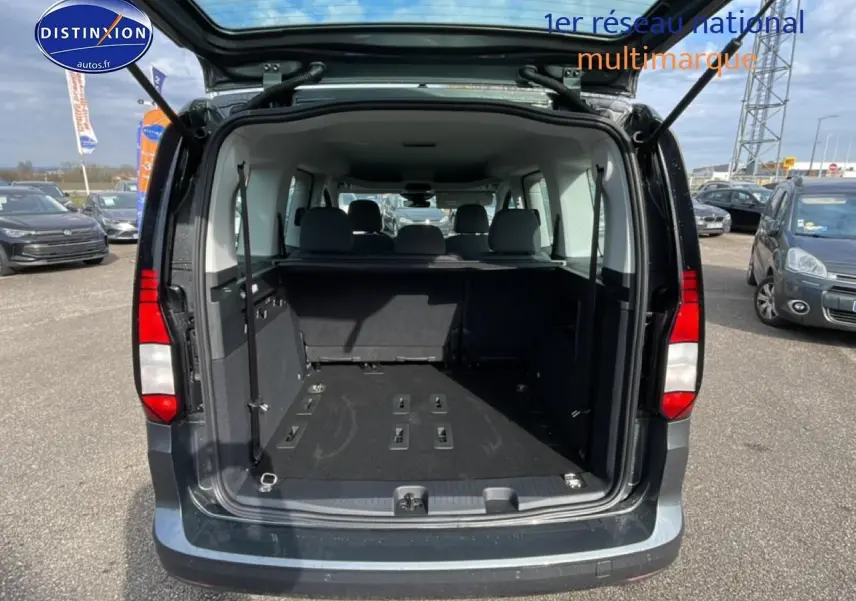 Vue arrière ouverte du Volkswagen Caddy gris indien 2025 montrant le grand espace de chargement et les sièges arrière.