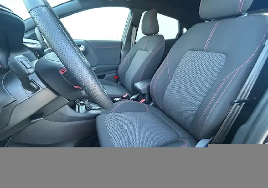 Intérieur avant du Ford Puma 2023, sièges noirs avec surpiqûres rouges et volant perforé ST-Line à méplat.