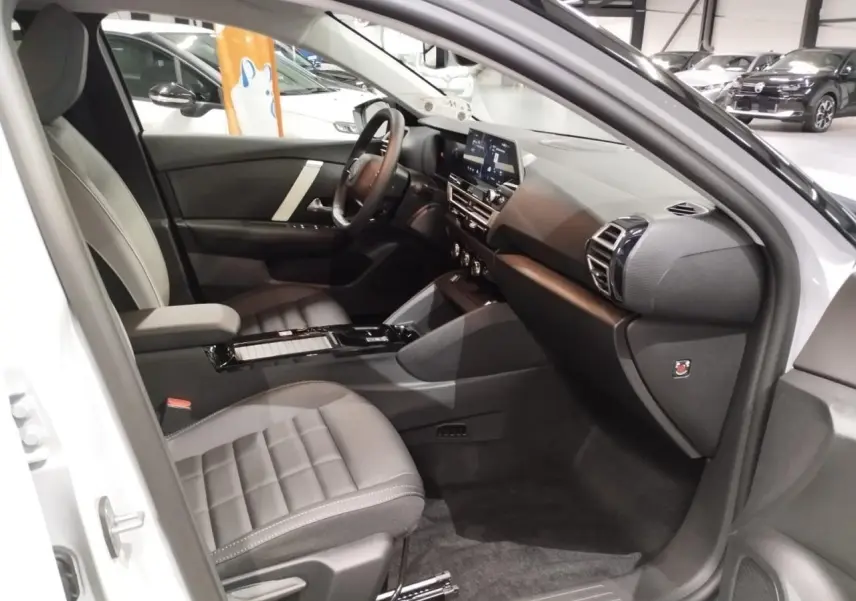 Vue intérieure côté passager avant de la Citroën C4 2025, sièges gris et tableau de bord noir moderne.