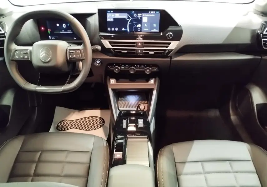 Intérieur avant de la Citroën C4 hybride 2025, vue du tableau de bord et console centrale noire avec écran tactile.