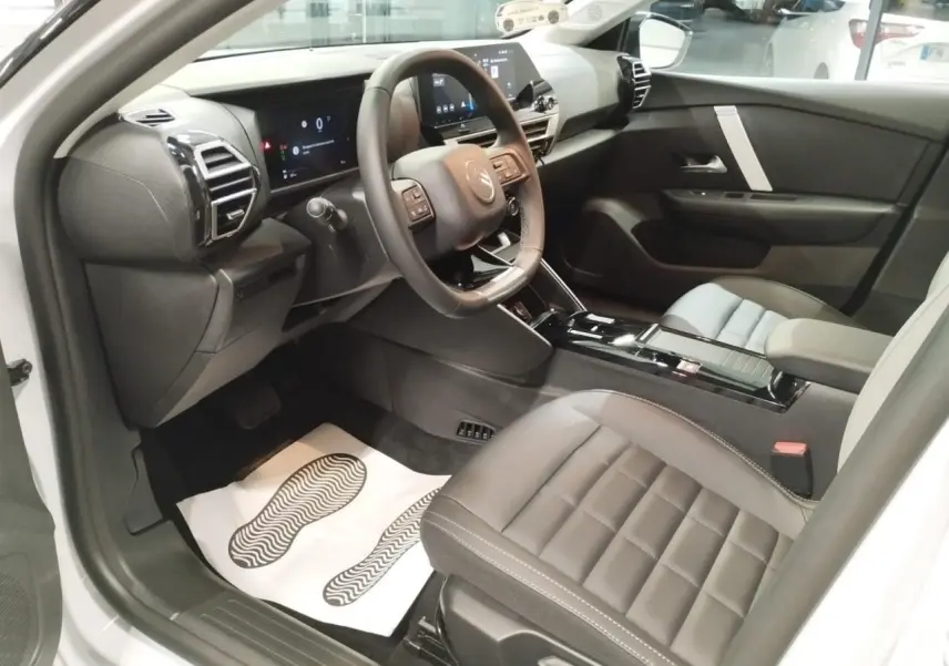 Intérieur avant droit de la Citroën C4 2025, sièges cuir gris, tableau de bord numérique et console centrale noire brillante.
