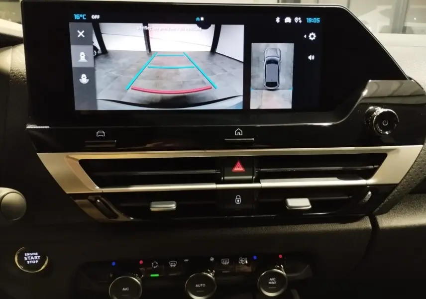Vue rapprochée de l’écran central tactile affichant la caméra de recul et les commandes de climatisation sur tableau de bord noir.