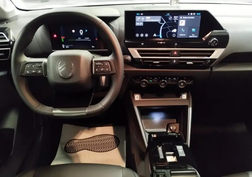 Vue intérieure frontale du tableau de bord et volant noir de la Citroën C4 2025 avec écran tactile et commandes intégrées.