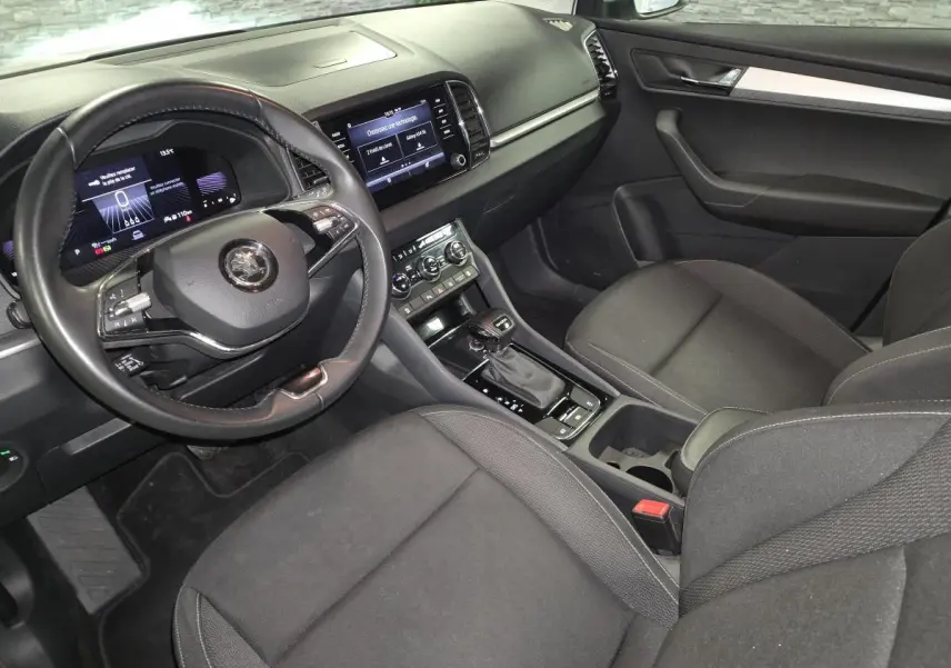 Intérieur avant droit de la Skoda Karoq 2023, tableau de bord noir avec écran tactile et volant cuir multifonctions.