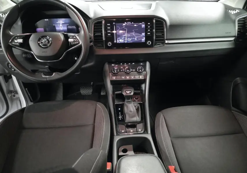 Vue intérieure avant du Skoda Karoq 2023, tableau de bord noir avec écran tactile et volant cuir multifonctions.