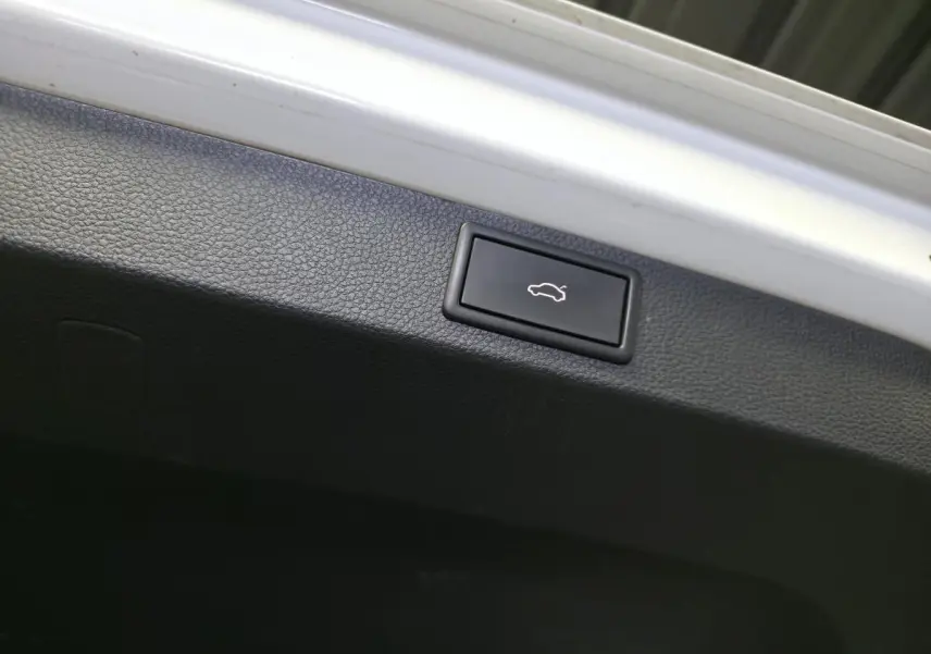 Bouton d'ouverture électrique du hayon sur la garniture intérieure noire d'un Skoda Karoq blanc.