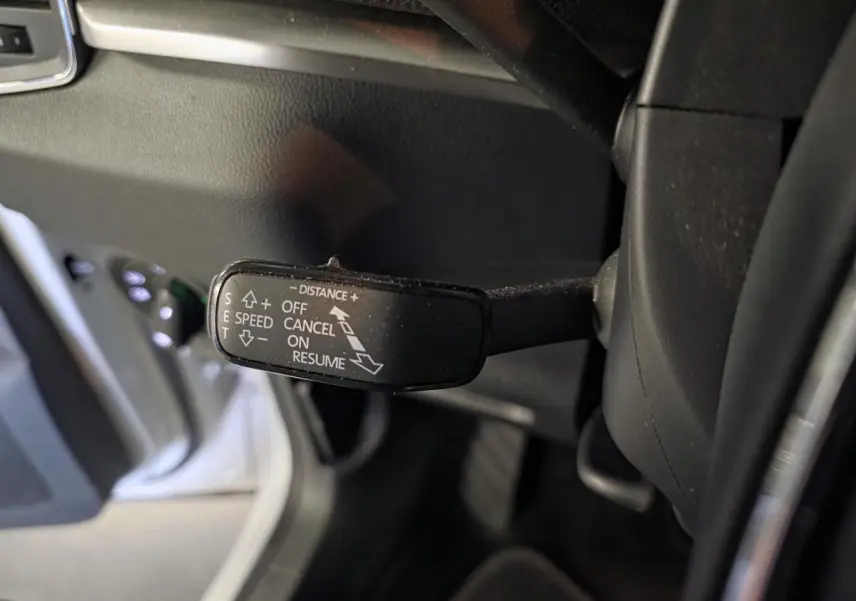 Gros plan sur la commande de régulateur de vitesse adaptatif dans l'habitacle du Skoda Karoq blanc 2023.