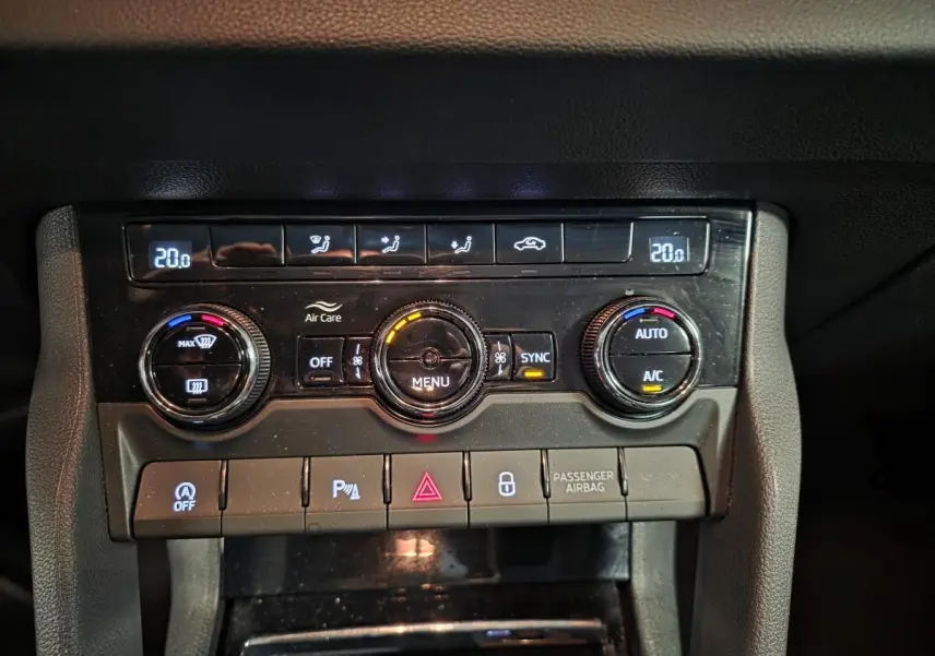 Vue rapprochée de la console centrale noire du Skoda Karoq 2023 avec commandes climatisation bi-zone et boutons fonctionnels.