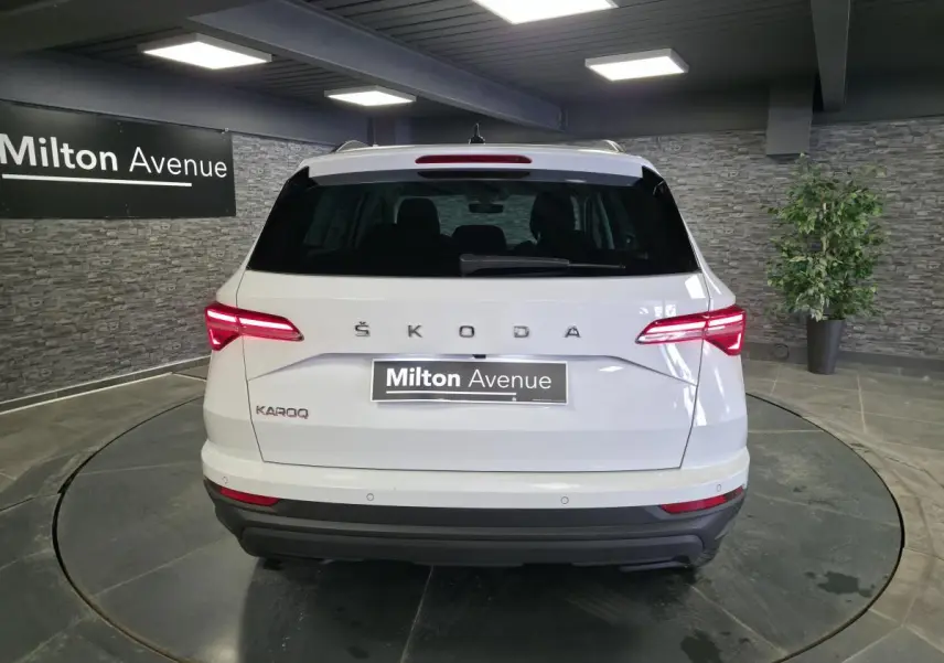 Vue arrière d'un Skoda Karoq blanc 2023 avec feux arrière LED allumés dans un showroom intérieur.