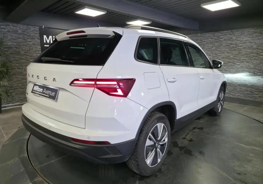 Vue 3/4 arrière droite d’un Skoda Karoq blanc 2023 avec feux arrière LED et jantes alliage 17 pouces.
