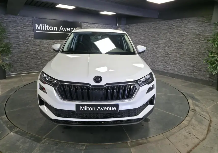Vue avant d'un Skoda Karoq blanc 2023 avec calandre noire et phares LED dans un showroom.
