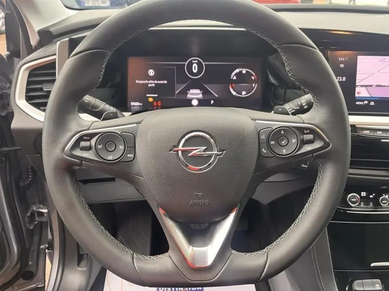 Vue intérieure centrée sur le volant cuir multifonction de l’Opel Grandland gris Kontrast, avec écran tactile et commandes visibles.