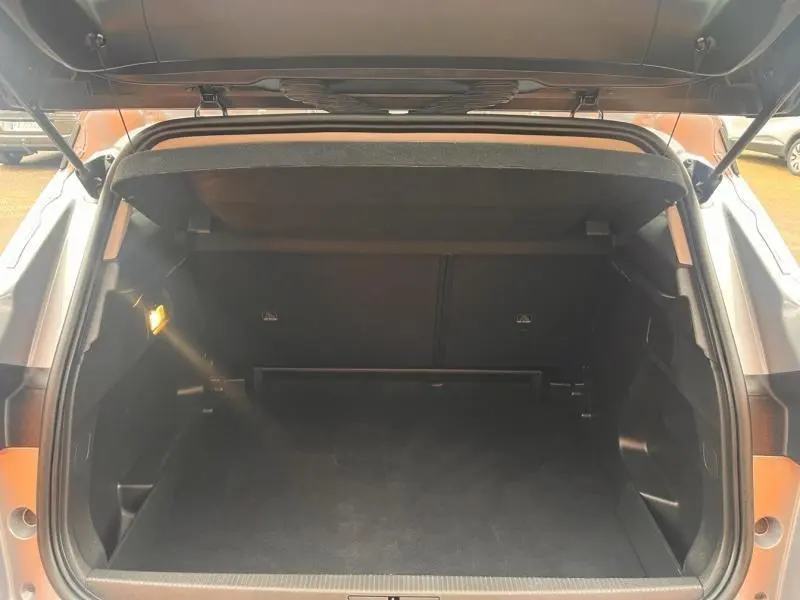 Coffre ouvert vu de l'arrière de l'Opel Grandland gris Kontrast métallisé avec cache-bagages et éclairage intérieur allumé.