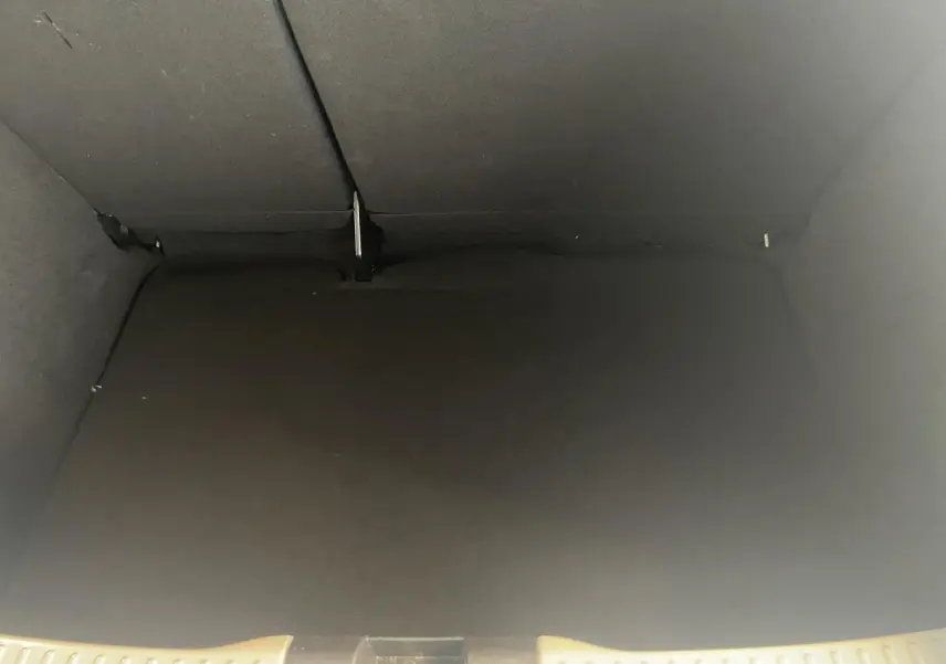 Vue intérieure du coffre noir spacieux de la Dacia Sandero 2024, version Expression blanche, avec banquette arrière rabattue.