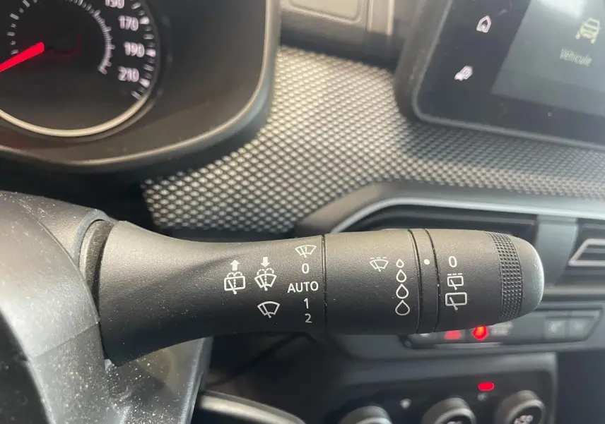 Gros plan sur la commande des essuie-glaces du tableau de bord d’une Dacia Sandero blanche 2024.