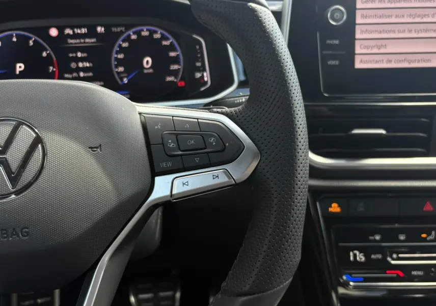Gros plan sur le volant cuir perforé et le tableau de bord digital du Volkswagen T-Roc 2025 noir intense, version R-Line.