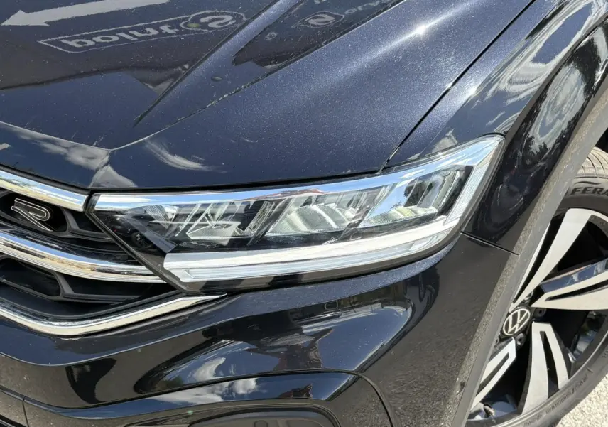 Gros plan sur l'avant droit noir intense du Volkswagen T-Roc 1.5 TSI R-Line avec phares LED et jante alliage Nevada.