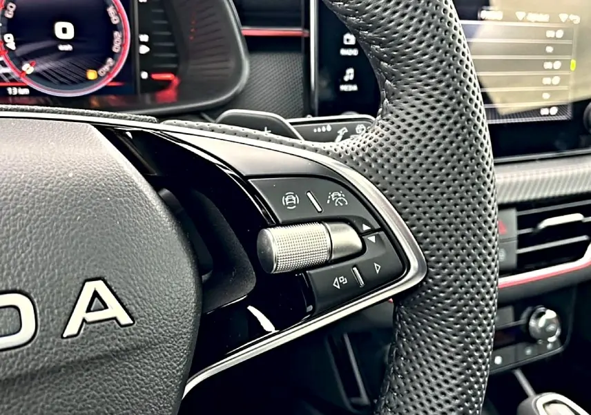 Gros plan sur le volant sport perforé noir du Skoda Kamiq 2026 avec commandes multifonctions et tableau de bord numérique.