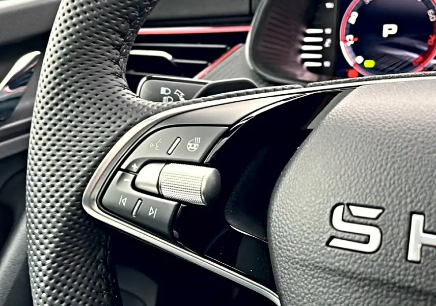 Gros plan sur la partie gauche du volant cuir perforé du Skoda Kamiq blanc nacré, avec commandes multifonctions et palettes.
