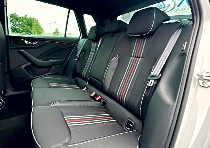 Vue intérieure côté droit sur la banquette arrière noire avec surpiqûres blanches et bandes rouges du Skoda Kamiq blanc nacré.