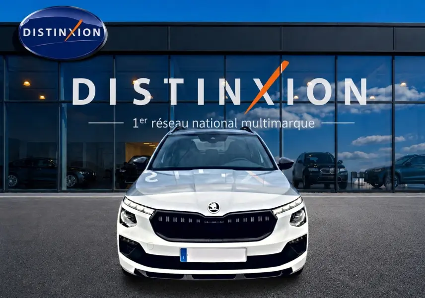 Vue frontale d'un Skoda Kamiq blanc nacré avec calandre noire et toit panoramique, devant une vitrine Distinxion.