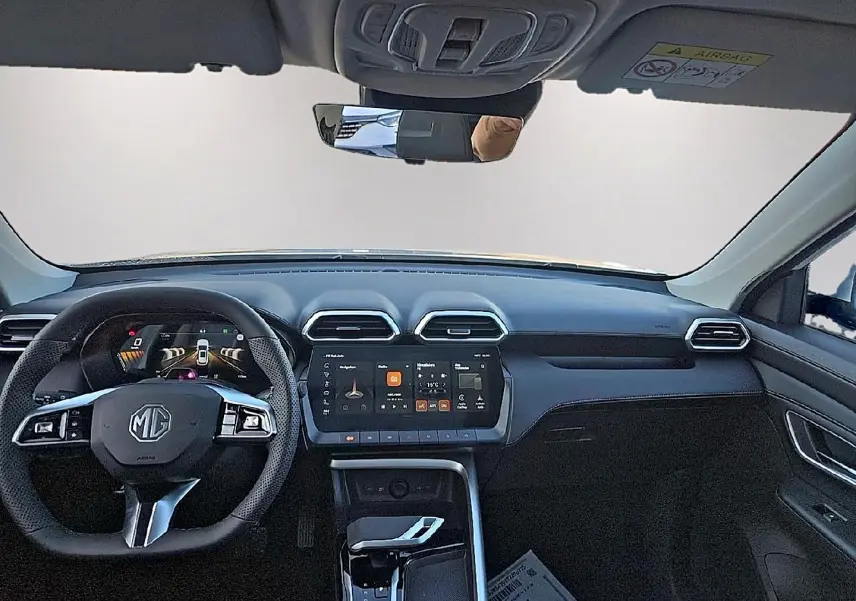 Vue frontale de l'habitacle noir du MG ZS 1.5 hybrid 197 luxury avec tableau de bord numérique et écran tactile central.
