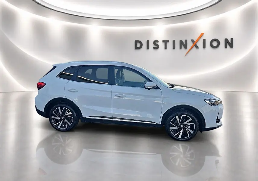 Vue de profil côté gauche du SUV blanc MG ZS 1.5 hybrid 197 luxury avec jantes alliage noires et toit panoramique.