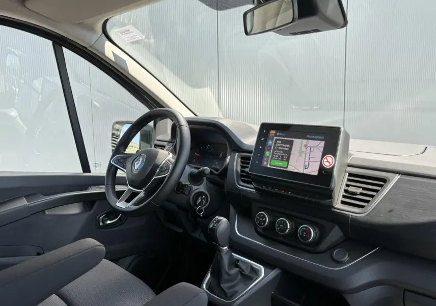 Vue intérieure côté conducteur du Renault Trafic Fourgon gris Urban, avec écran tactile multimédia et volant multifonction.