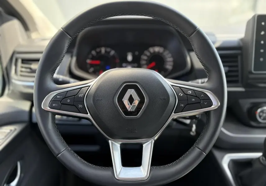 Volant en cuir noir avec logo Renault au centre, tableau de bord flou en arrière-plan, intérieur du Trafic Fourgon 2024.