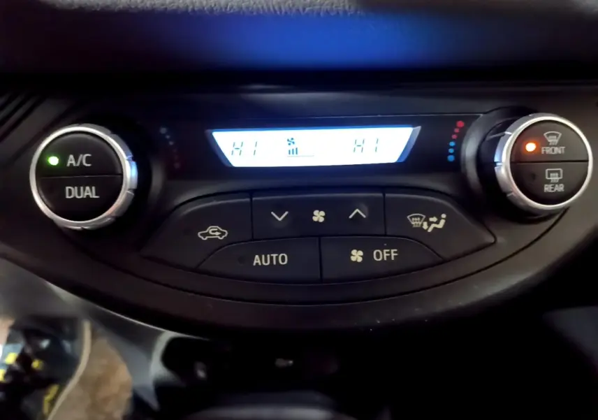 Vue rapprochée du panneau de climatisation 2 zones de la Toyota Yaris hybride 2019 avec affichage digital et boutons lumineux.