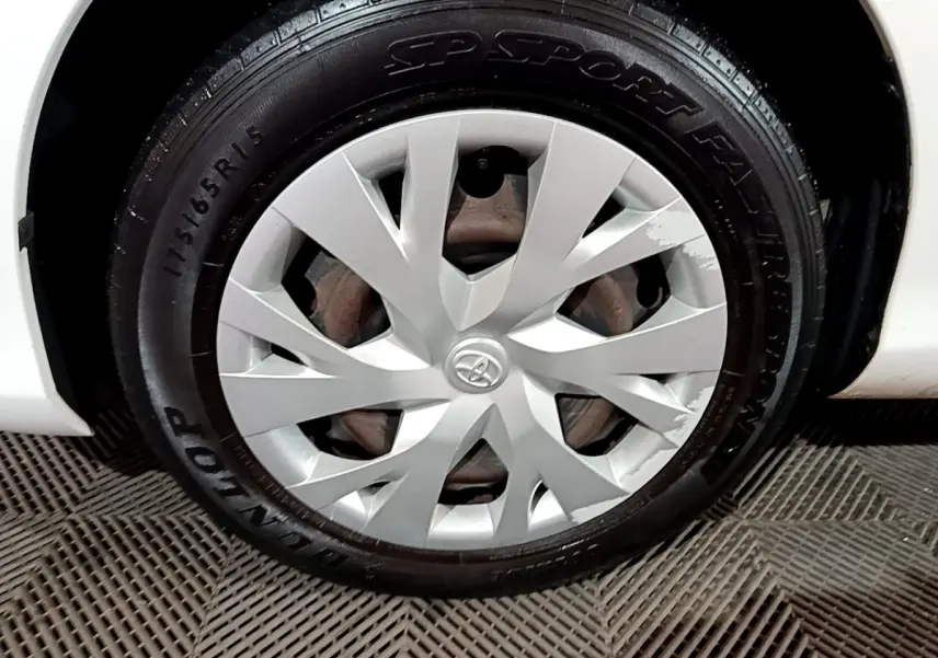 Gros plan sur la roue avant droite blanche d'une Toyota Yaris 1.5 Hybrid avec enjoliveur Toyota argenté.