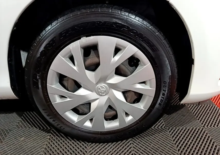 Gros plan sur la roue avant droite blanche d'une Toyota Yaris 1.5 VVT-I Hybrid avec enjoliveur argenté Toyota.