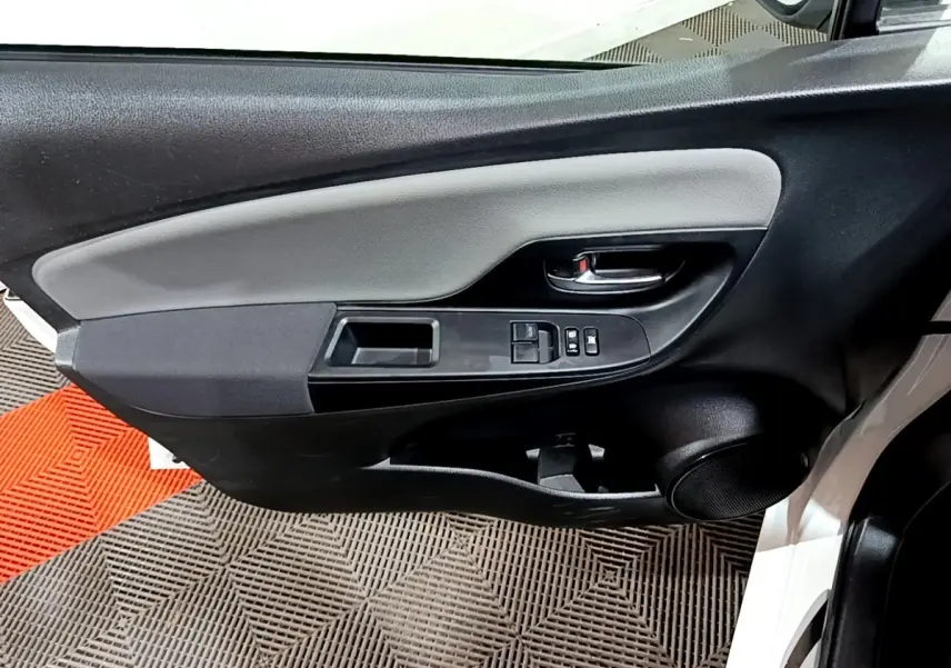 Gros plan sur la porte avant gauche blanche d'une Toyota Yaris 2019, avec commandes électriques et haut-parleur intégré.