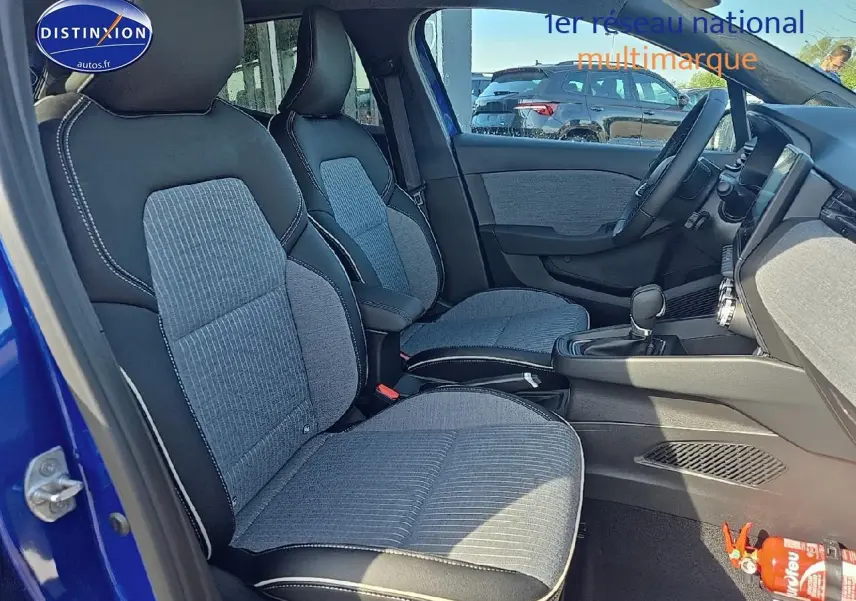 Vue intérieure côté gauche montrant les sièges avant en tissu gris et noir d'une Renault Clio V Bleu Iron 2025.