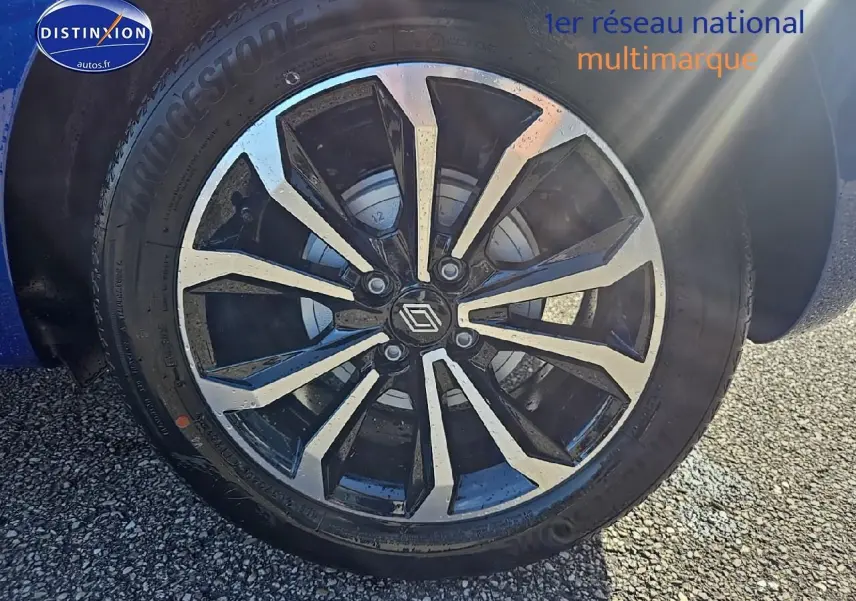 Gros plan sur la jante alu bicolore de la Renault Clio V Bleu Iron, avec logo Renault au centre.